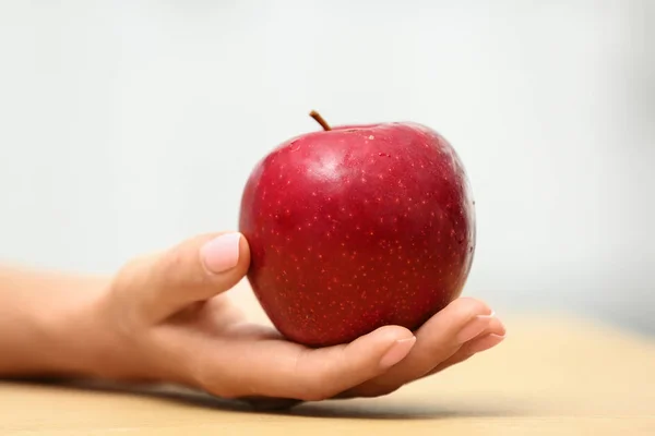 Mulher segurando maçã vermelha fresca na mesa, close-up — Fotografia de Stock