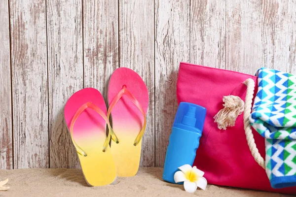 Samenstelling met stijlvolle zomer strand accessoires op zand in de buurt van houten muur — Stockfoto