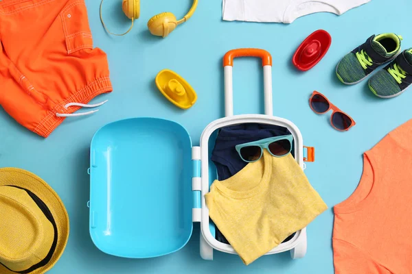 青い背景に子供のスーツケースやアクセサリーとフラットレイの組成。夏休み — ストック写真
