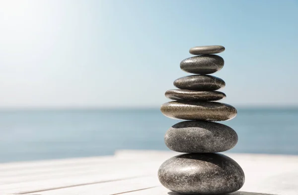 Steinstapel auf Holzpier in der Nähe des Meeres, Platz für Text. zen-Konzept — Stockfoto