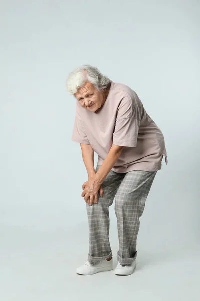 Full längd porträtt av Senior Kvinna med knäproblem på grå bakgrund — Stockfoto
