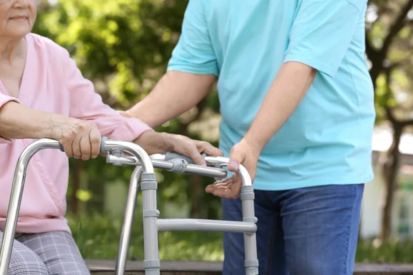 Äldre man hjälpa sin fru med promenad ram utomhus, närbild Royaltyfria Stockfoton