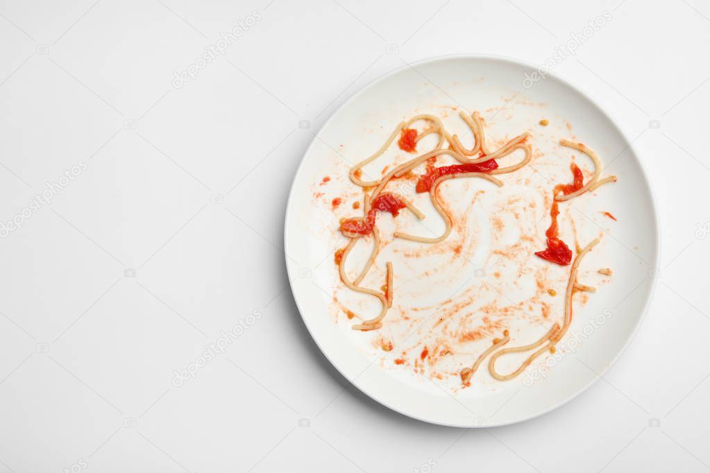 Dirty plate with food leftovers on white background, top view