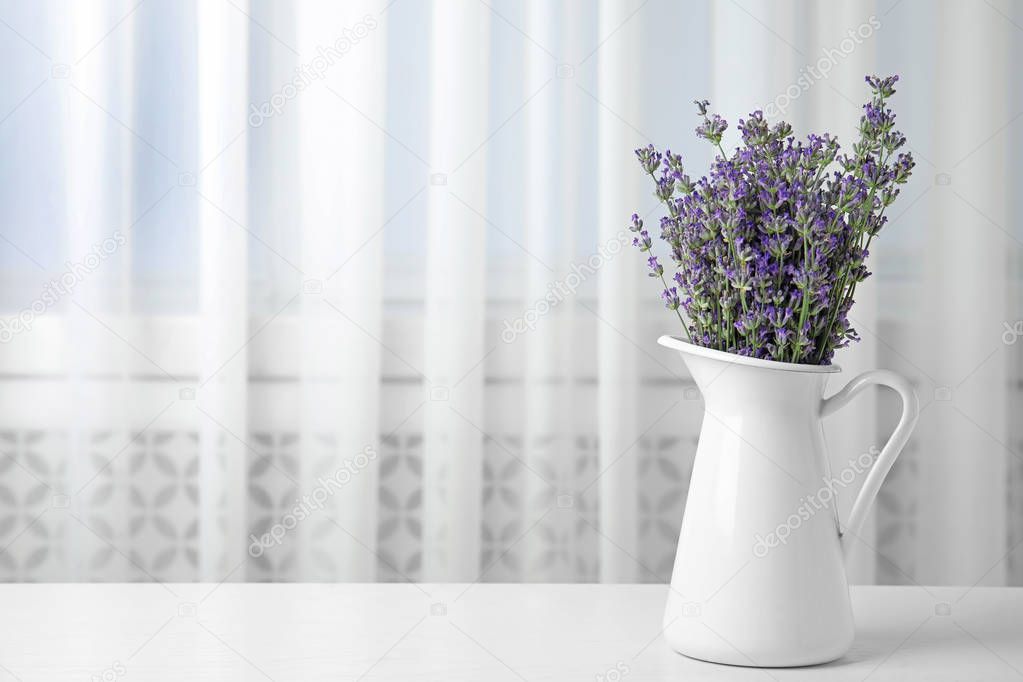 Beautiful tender lavender flowers in jug on white table indoors, space for text