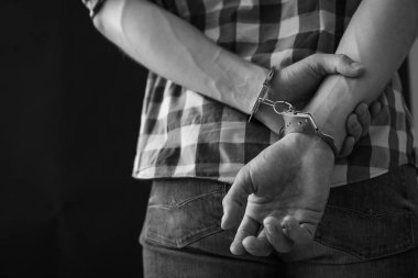 Karanlık arka plana karşı kelepçeli olarak gözaltına alınan suçlu, metin için yer. Siyah beyaz etkisi