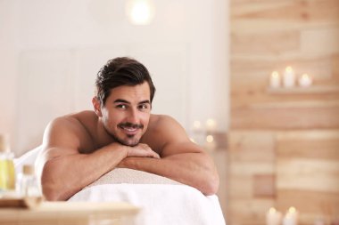 Yakışıklı genç adam spa salonunda masaj masasında rahatlatıcı, metin için alan
