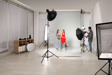 Modern stüdyoda model ile çalışan profesyonel fotoğrafçı ve asistan