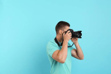 Genç profesyonel fotoğrafçı açık mavi arka plan üzerinde fotoğraf çekiyor. Metin için alan