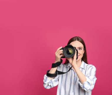 Profesyonel fotoğrafçı pembe arka planda fotoğraf çekiyor. Metin için alan