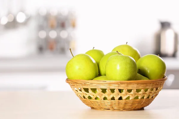 Ciotola di vimini con mele verdi dolci sul tavolo in cucina, spazio per il testo — Foto Stock