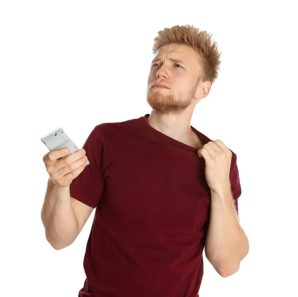 Mladý muž s klimatizací vzdálené trpící teplem na bílém pozadí — Stock fotografie