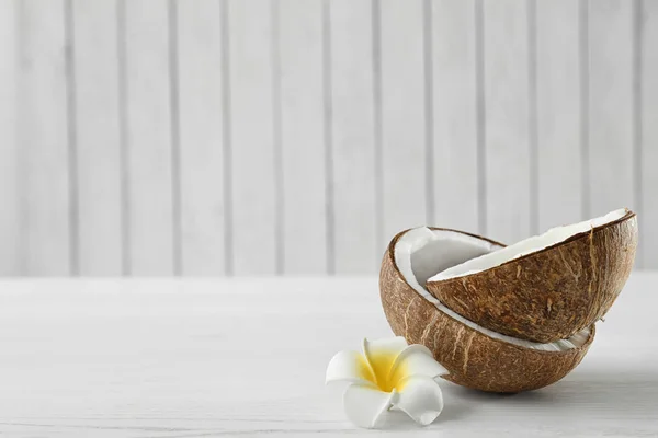 Metades de coco e flor na mesa de madeira branca. Espaço para texto — Fotografia de Stock