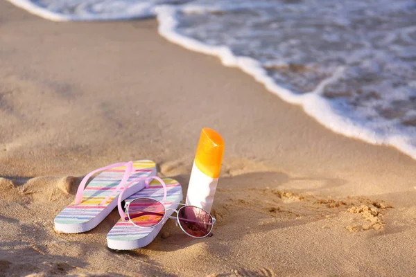 Chanclas y accesorios de playa en arena cerca del mar. Espacio para texto —  Fotos de Stock