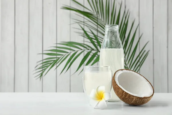 Composição com garrafa e vidro de água de coco sobre mesa de madeira branca — Fotografia de Stock