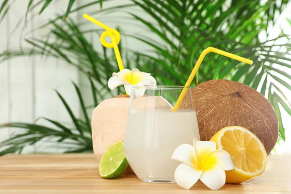 Композиція зі склянкою кокосової води на дерев'яному столі на розмитому фоні — стокове фото