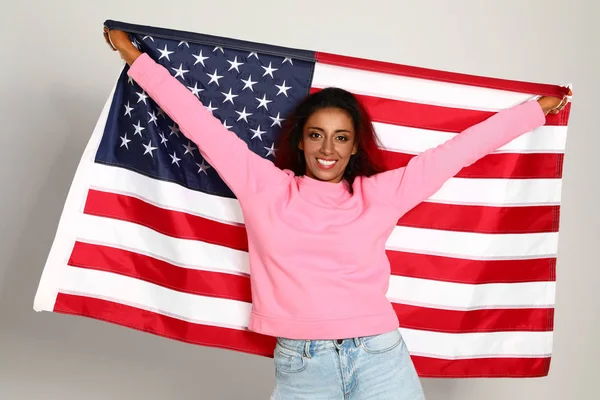 Beautiful Hispanic woman with US flag on light background