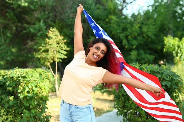 Beautiful Hispanic woman with US flag in park — Stock Photo, Image