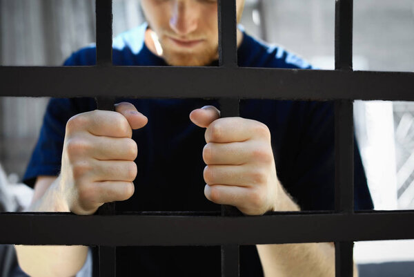 Man detained in jail outdoors, closeup. Criminal law