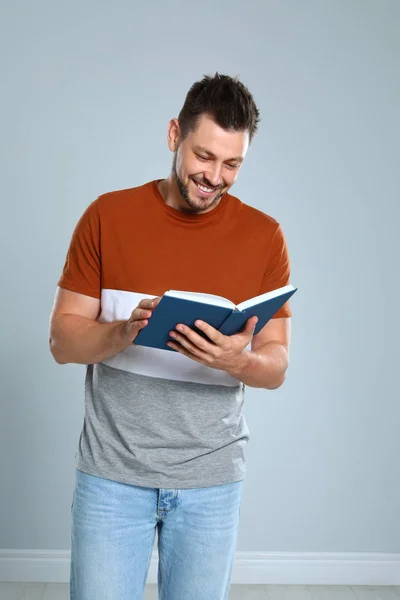 Przystojny mężczyzna czytania książki przed jasnym tle — Zdjęcie stockowe
