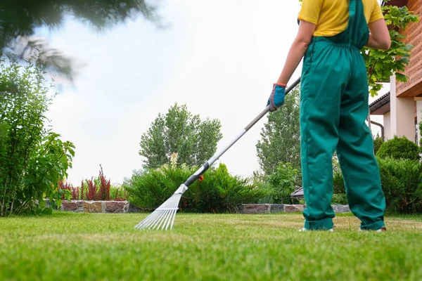 Frau harkt grünen Rasen im Hinterhof. Gartenarbeit zu Hause — Stockfoto