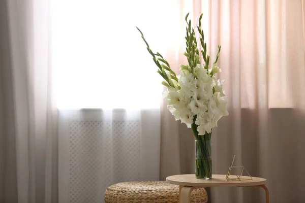 Vase with beautiful white gladiolus flowers on wooden table in room, space for text — Stock Photo, Image