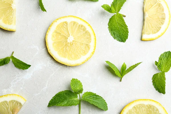 Fresh mint with sliced lemon on grey marble background, flat lay — Stock Photo, Image