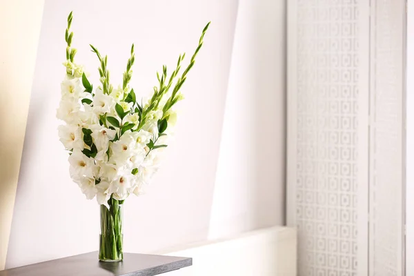Vas dengan bunga gladiolus putih yang indah di meja kayu dekat dinding warna. Ruang untuk teks — Stok Foto