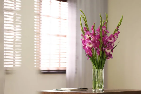 Jarrón con hermosas flores de gladiolo rosa en la mesa de madera en la habitación, espacio para el texto — Foto de Stock