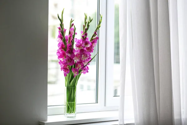 Jarrón con hermosas flores de gladiolo rosa en el alféizar de la ventana, espacio para el texto — Foto de Stock