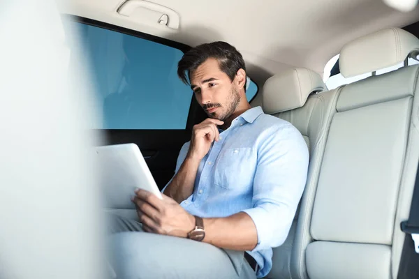 Ragazzo premuroso con tablet sul sedile posteriore in auto di lusso — Foto Stock