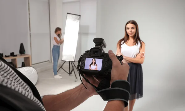 Professional photographer reviewing picture on camera and model with assistant in studio — Stock Photo, Image