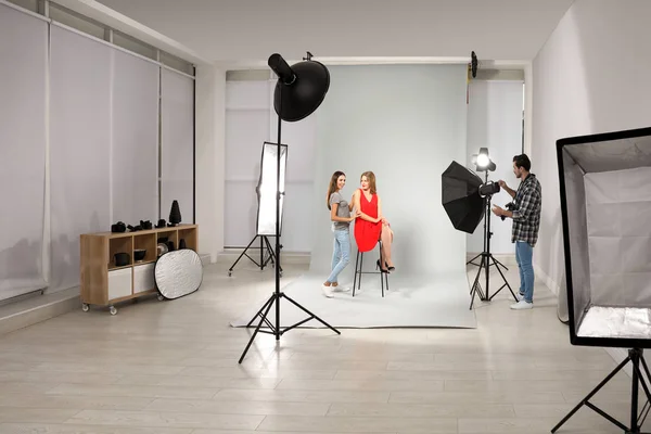 Fotógrafo profesional y asistente trabajando con modelo en estudio moderno — Foto de Stock