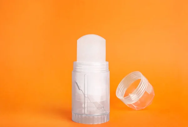 Desodorante y tapa de palo de alumbre de cristal natural sobre fondo naranja — Foto de Stock