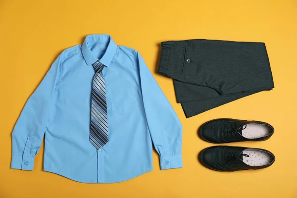 Composição de leigos plana com uniforme escolar no fundo amarelo — Fotografia de Stock