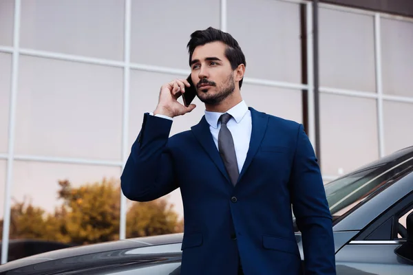 Attraente giovane uomo che parla al telefono vicino auto di lusso all'aperto — Foto Stock