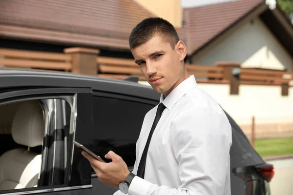 Atractivo joven con teléfono inteligente cerca de coches de lujo al aire libre — Foto de Stock