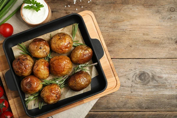 Leckere heiße Ofenkartoffeln mit saurer Sahne auf hölzernem Hintergrund, flache Lage — Stockfoto