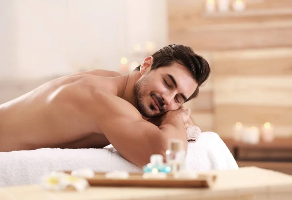 Schöner junger Mann entspannt auf Massagetisch im Wellness-Salon, Platz für Text — Stockfoto