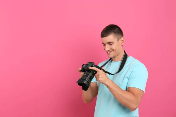 Ung fotograf med professionell kamera på rosa bakgrund. Utrymme för text — Stockfoto