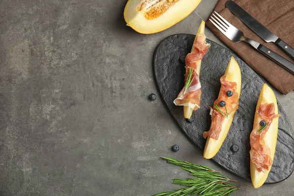 Flat lay composition of fresh melon with prosciutto on grey table. Space for text — Stock Photo, Image