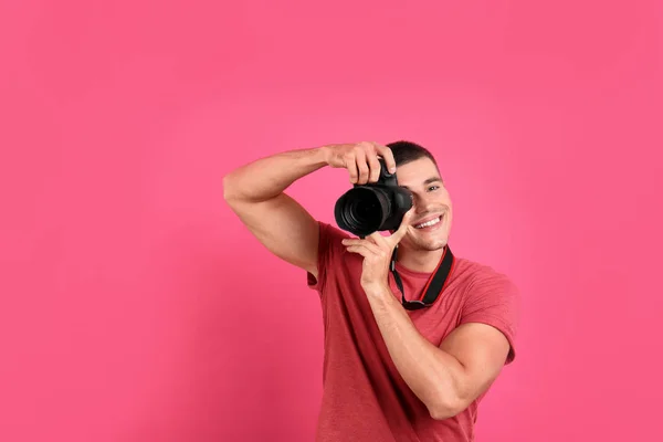 年轻的专业摄影师在粉红色的背景下拍照。文本空间 — 图库照片
