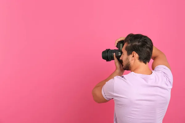 Ung professionell fotograf tar bild på rosa bakgrund. Utrymme för text — Stockfoto
