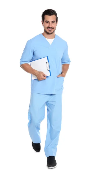 Young male doctor with clipboard walking on white background. Medical service — Stock Photo, Image