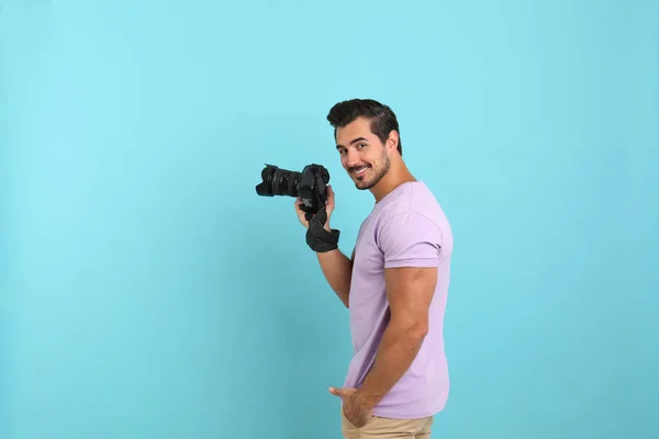 Junger Fotograf mit professioneller Kamera auf hellblauem Hintergrund. Raum für Text — Stockfoto