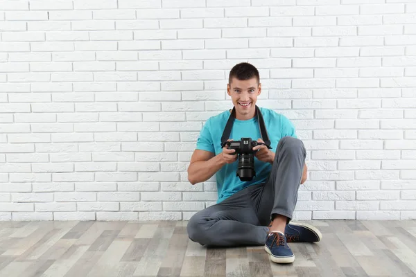 Fiatal fotós professzionális kamerával közel téglafal. Szóköz a szöveghez — Stock Fotó
