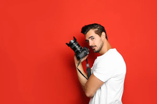 Joven fotógrafo con cámara profesional sobre fondo rojo. Espacio para texto —  Fotos de Stock