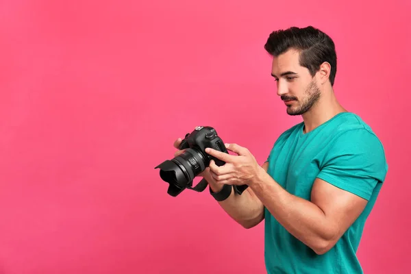 Mladý fotograf s profesionálním fotoaparátem na růžovém pozadí. Místo pro text — Stock fotografie