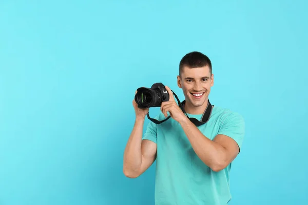 Jovem fotógrafo com câmera profissional em fundo azul claro. Espaço para texto — Fotografia de Stock