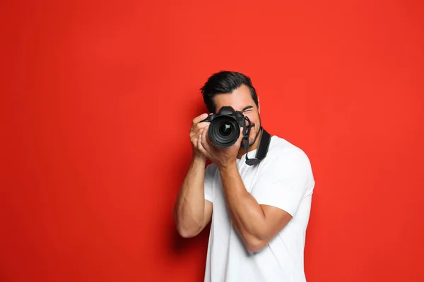 Joven fotógrafo profesional tomando fotos sobre fondo rojo. Espacio para texto —  Fotos de Stock