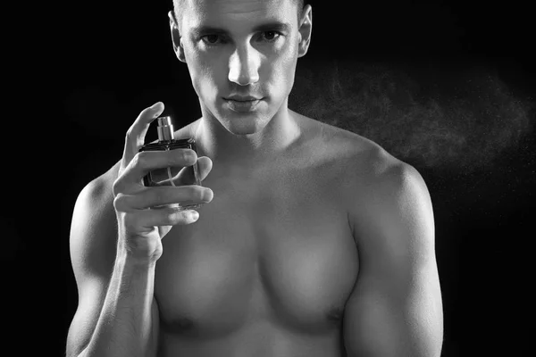 Hombre joven guapo rociando perfume, efecto blanco y negro —  Fotos de Stock